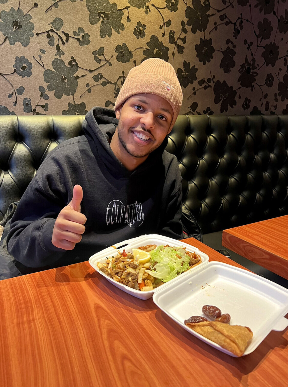 Idiris Awil er smilende fornøyd med iftar – måltidet i restauranten.