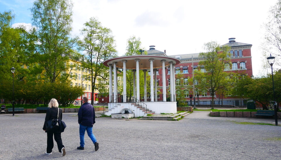 To forbipasserende går forbi paviljongen på Birkelunden – stedet som snart fylles med kor, fest og nasjonaldagsstemning.